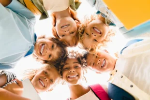 low angle view of a group of mixed race multi ethnic classmates schoolchildren standing in round
